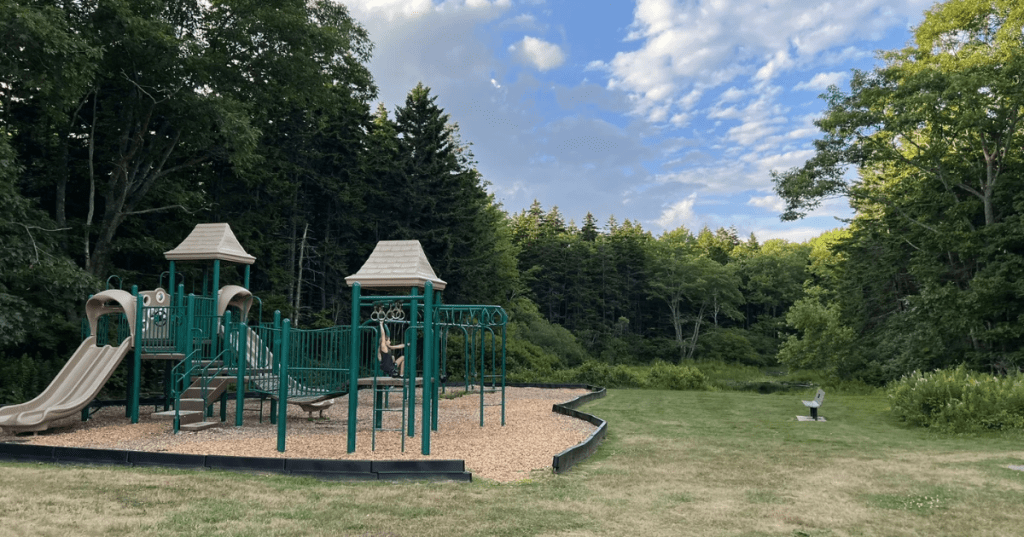 A playground surrounded by green trees at the Two Lights State Park in Cape Elizabeth, Maine.