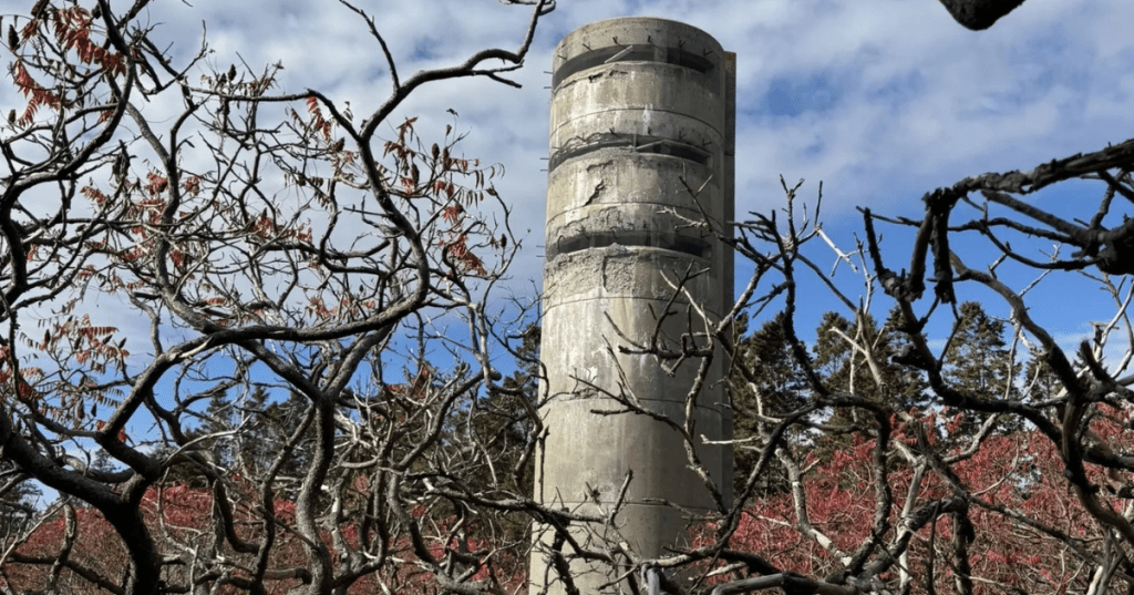 An old military fire towers stands behind tree branches at the Two Lights State Park in Cape Elizabeth, Maine.