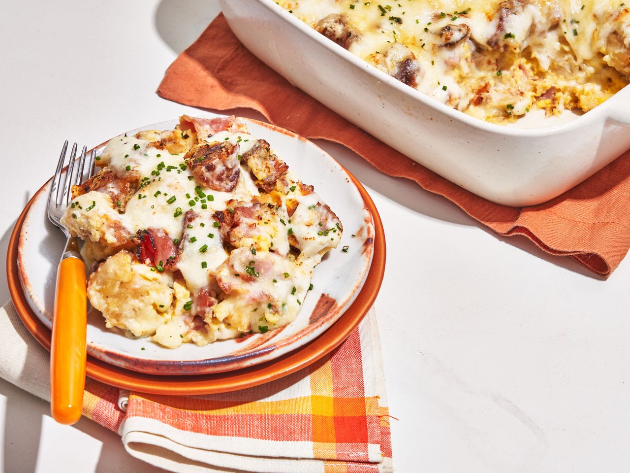 plated croque monsieur casserole with casserole dish in background and colorful orange and yellow tableware