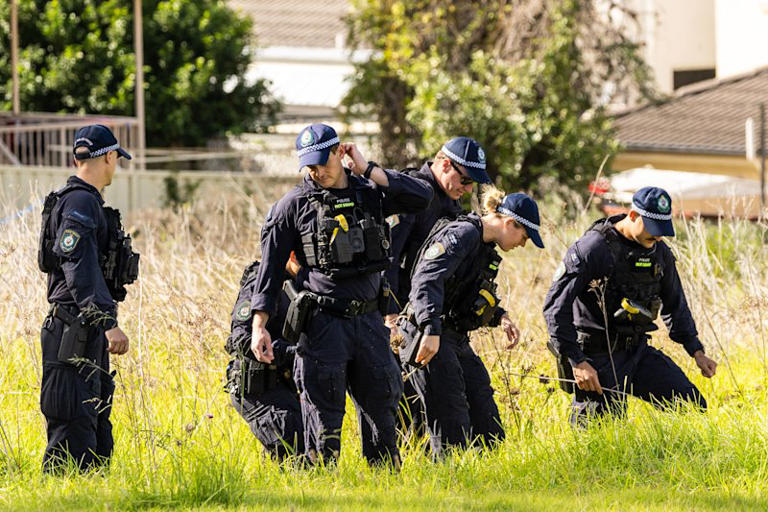 Police conduct a line search outside the Casula property.