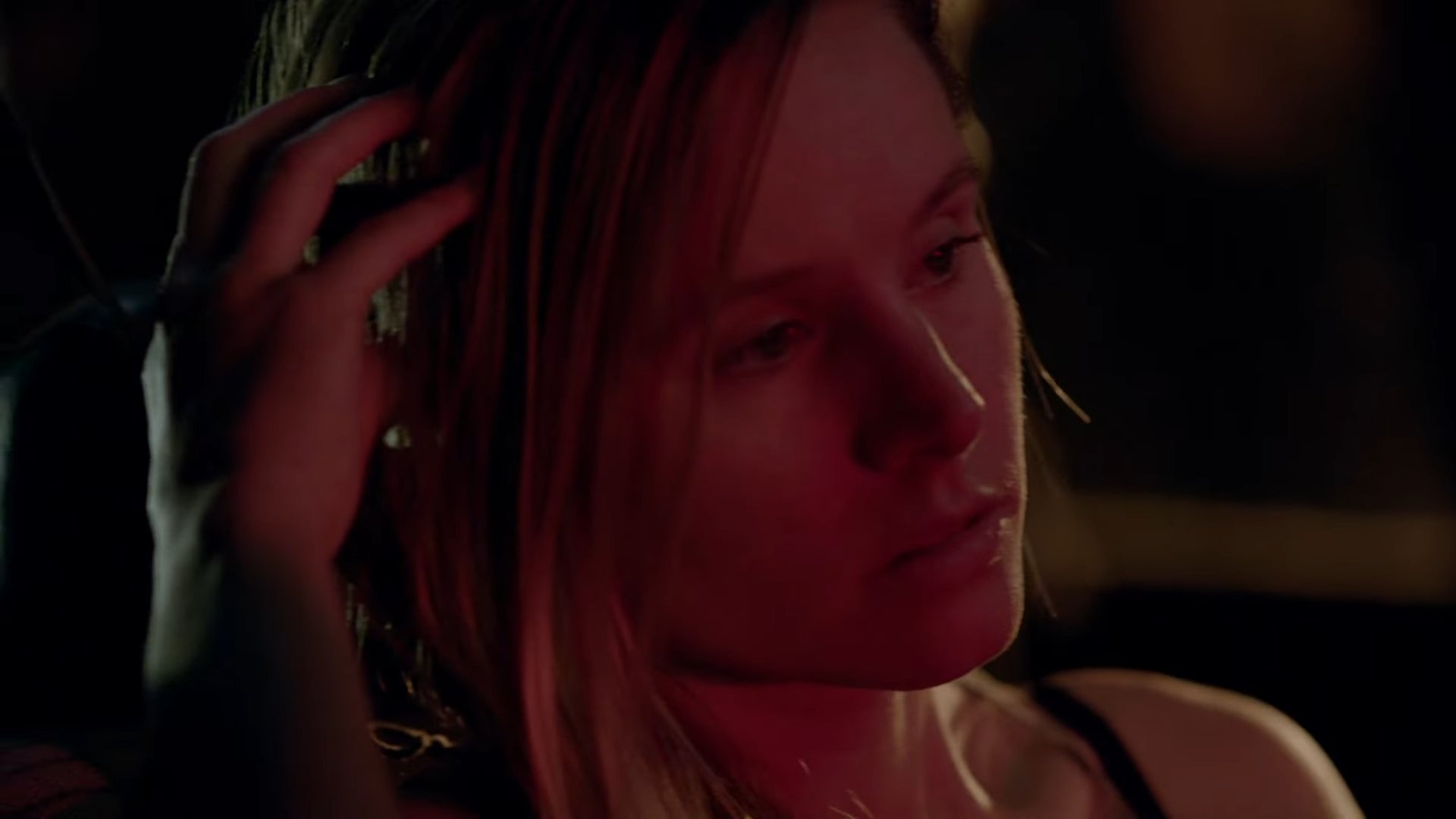 Person with a thoughtful expression, resting their hand on their head. The setting appears dimly lit