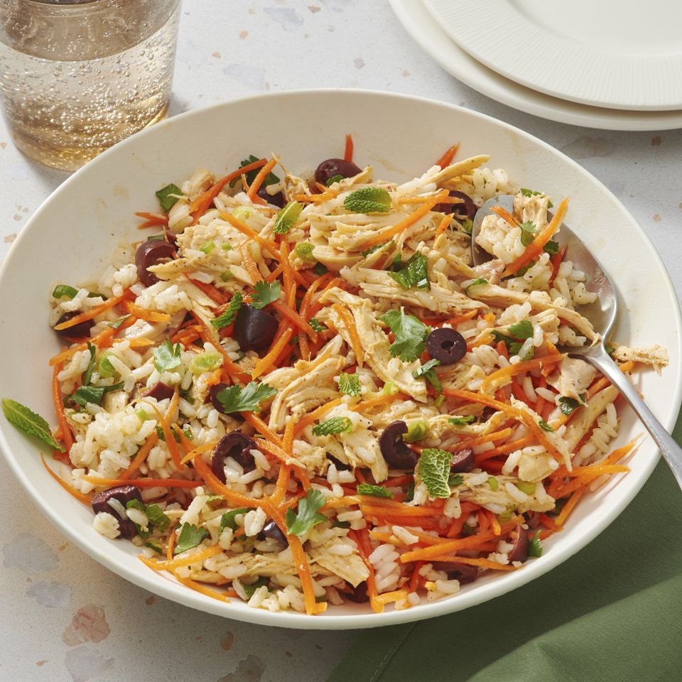 Bowl of herbed chicken salad with shredded chicken carrots rice and herbs