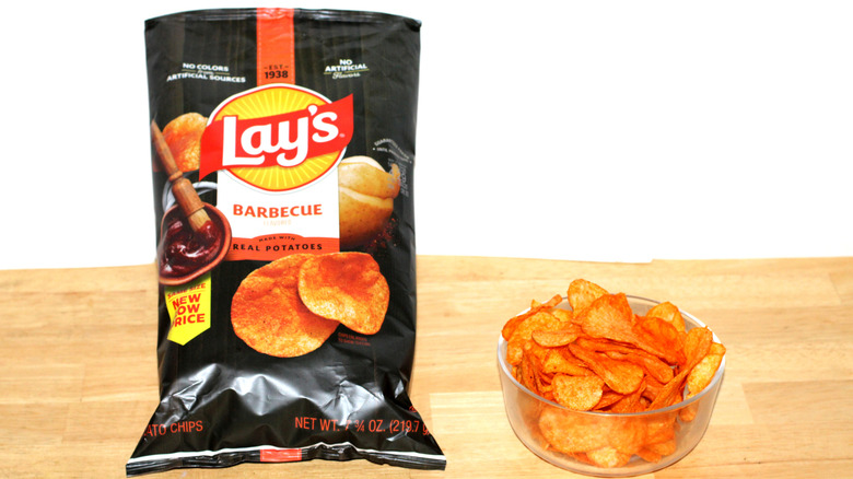 A bag of Lay's Barbecue potato chips beside a bowl full of chips