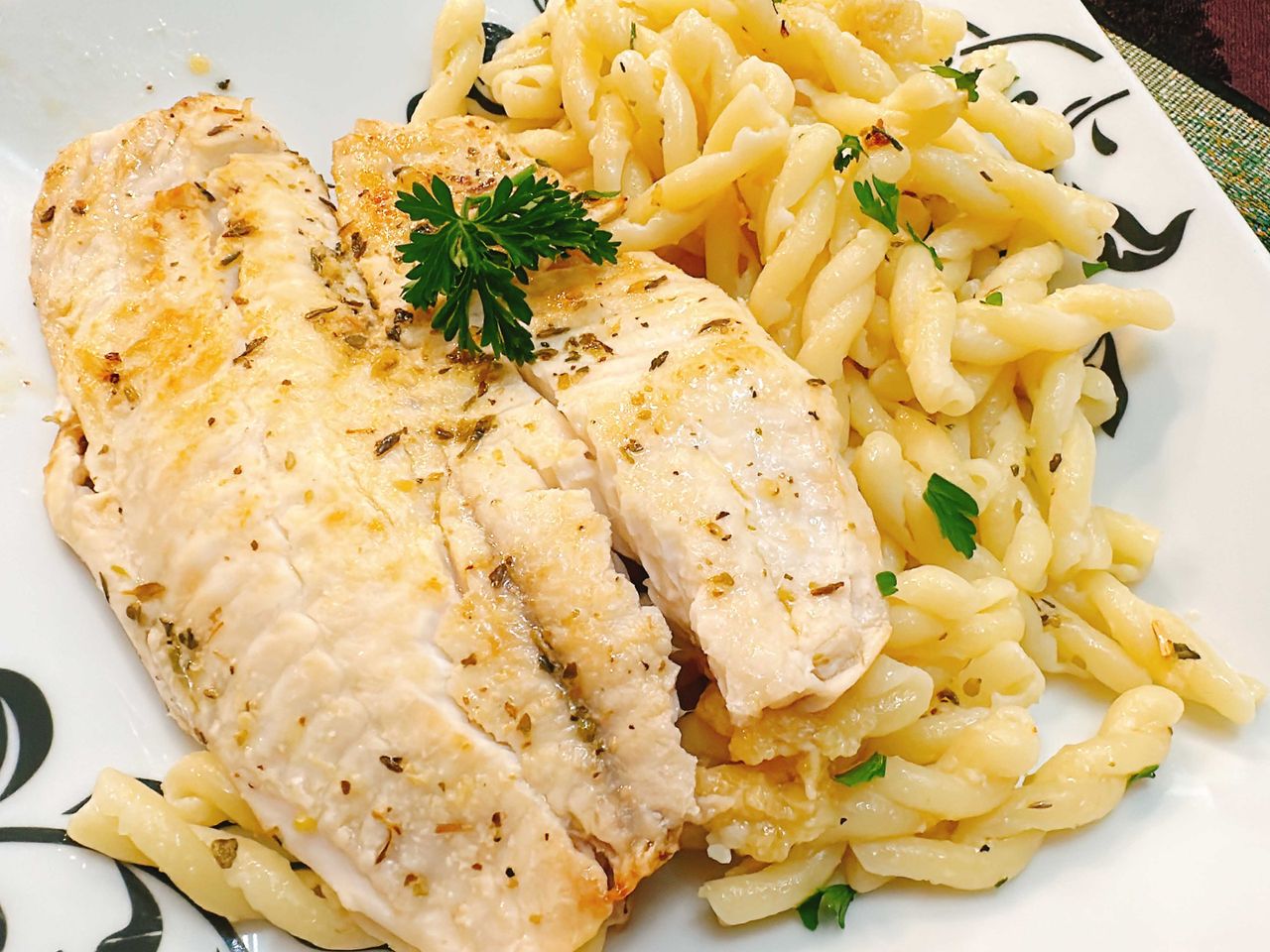 Pan seared timapia garnished with parsley with Parmesan pasta on the side