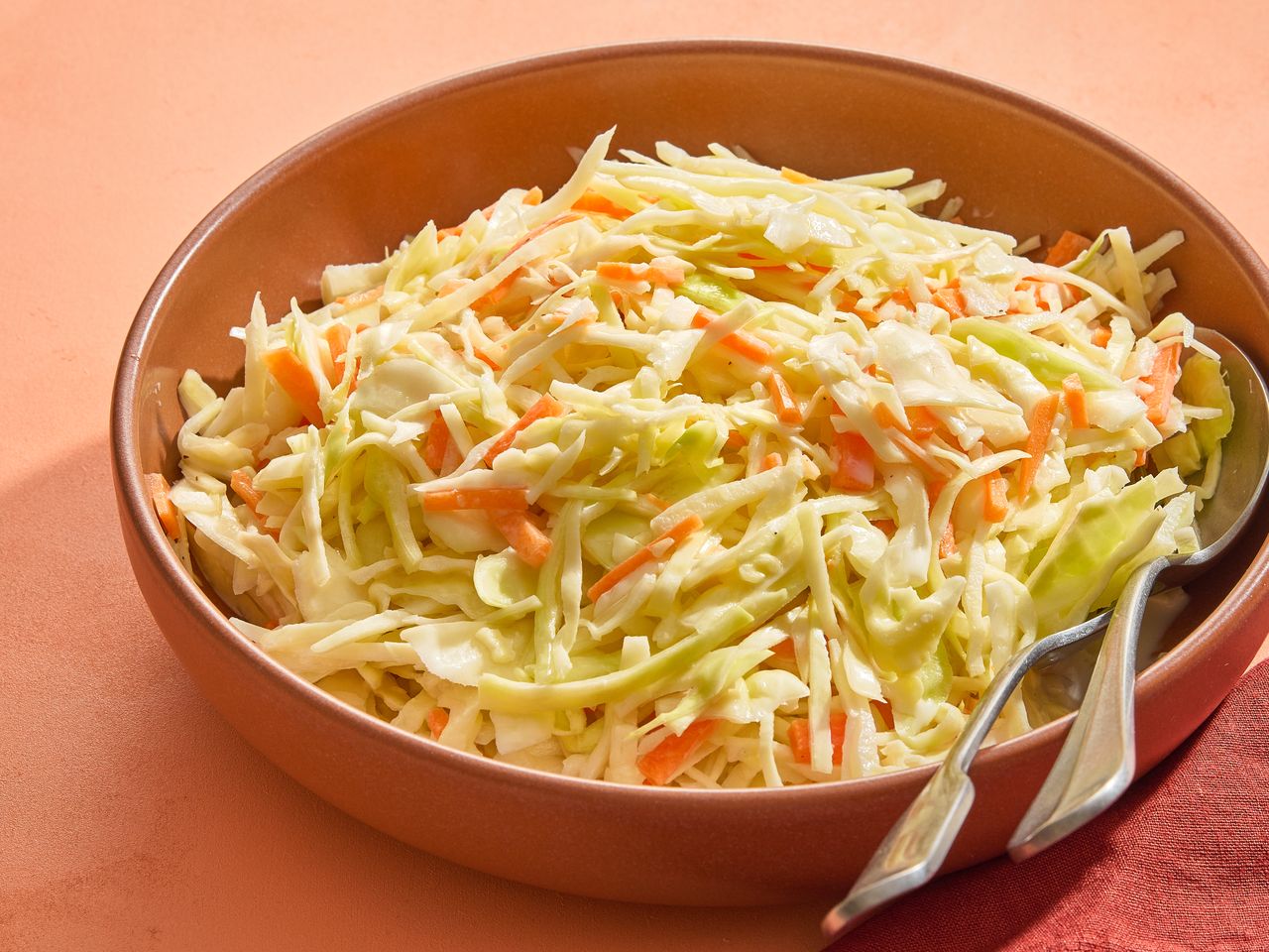 A bowl of freshly made coleslaw on an orange surface.