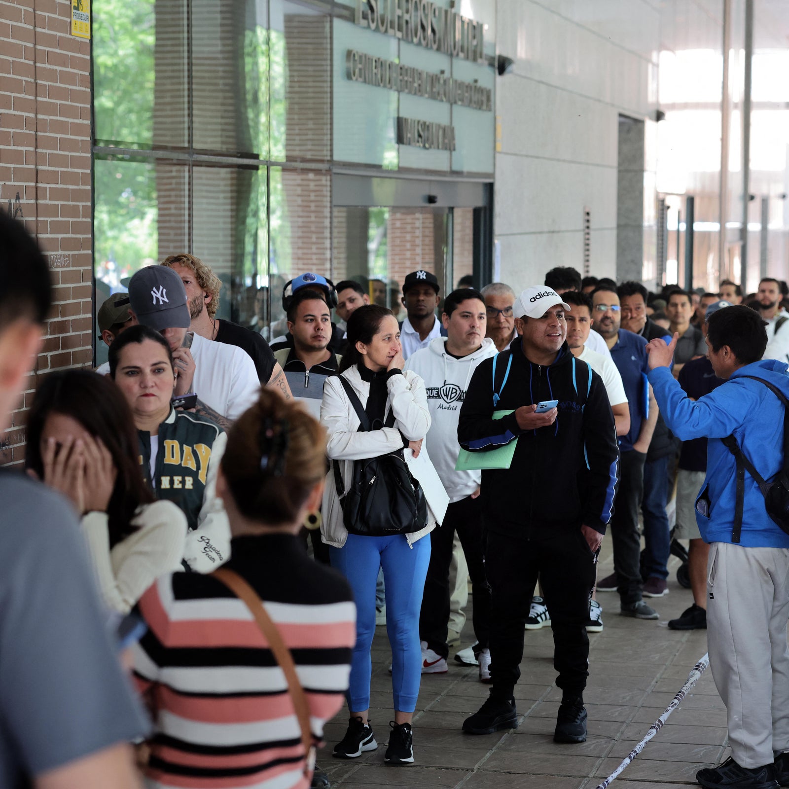 People wait in a line to enter the Spanish Commission For Refugee Aid (CEAR) in Madrid, Spain, April 22, 2026, to apply for regularized immigration status under an amnesty program for undocumented migrants approved by Spain's left-wing government.