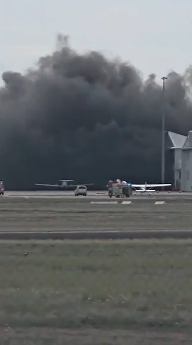 Thick black smoke drifted over the tarmac.