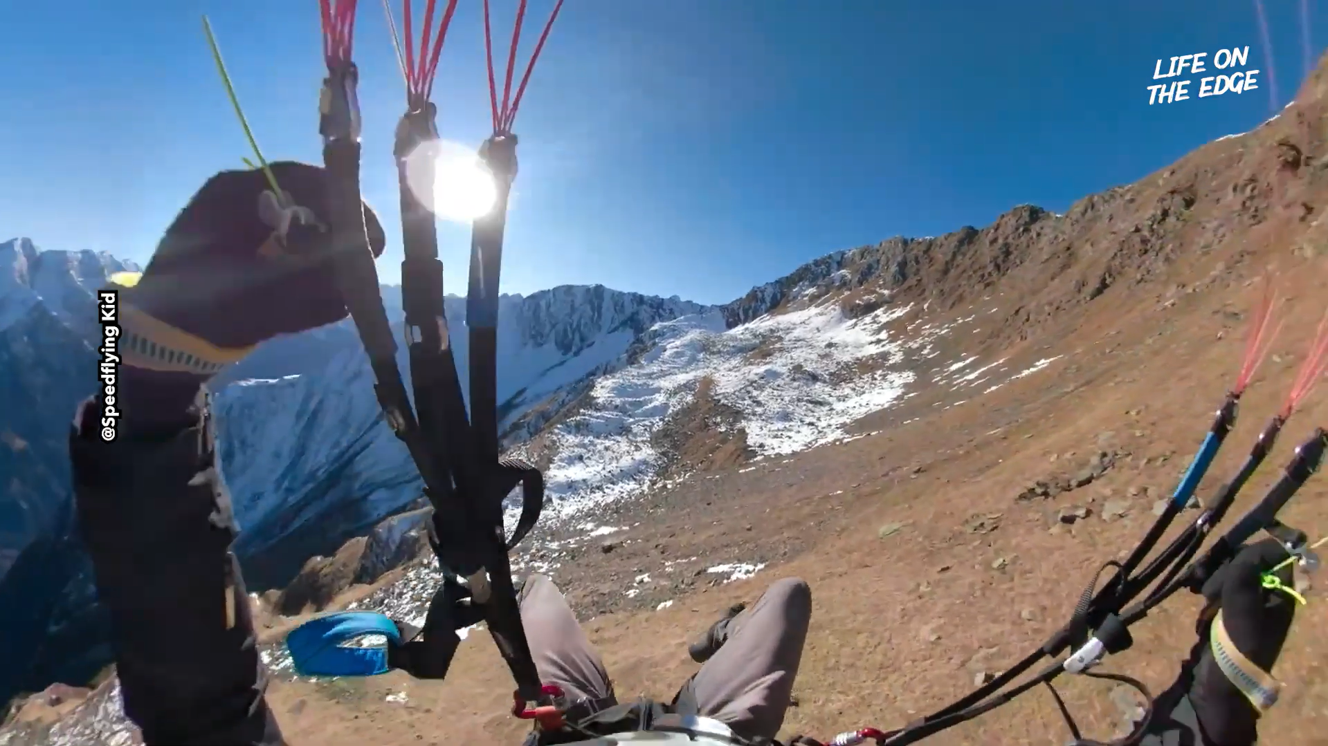 Speedflying down breathtaking ridge in alpine descent