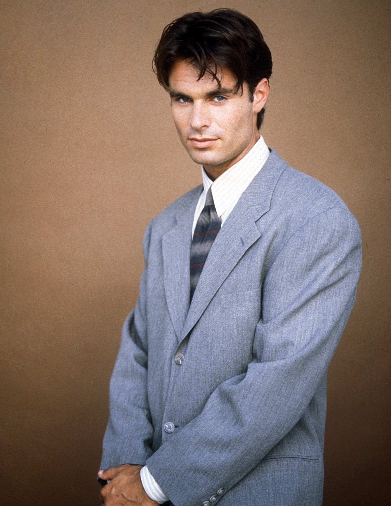 Portrait of Patrick Muldoon in a gray suit, white shirt, and striped tie, from the TV series Melrose Place.