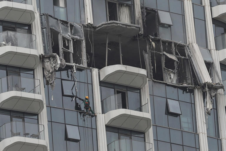 A worker assesses the damage after a building was hit by a reported drone strike in Dubai's Creek Harbour on March 12.