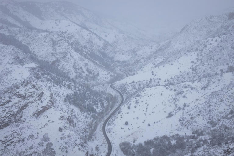 A mountain road winding through a canyon during a snowy winter whiteout in the Front Range of the Rockies in Colorado. The Rocky Mountains could see up to 13 inches of snow with the incoming snowstorm.