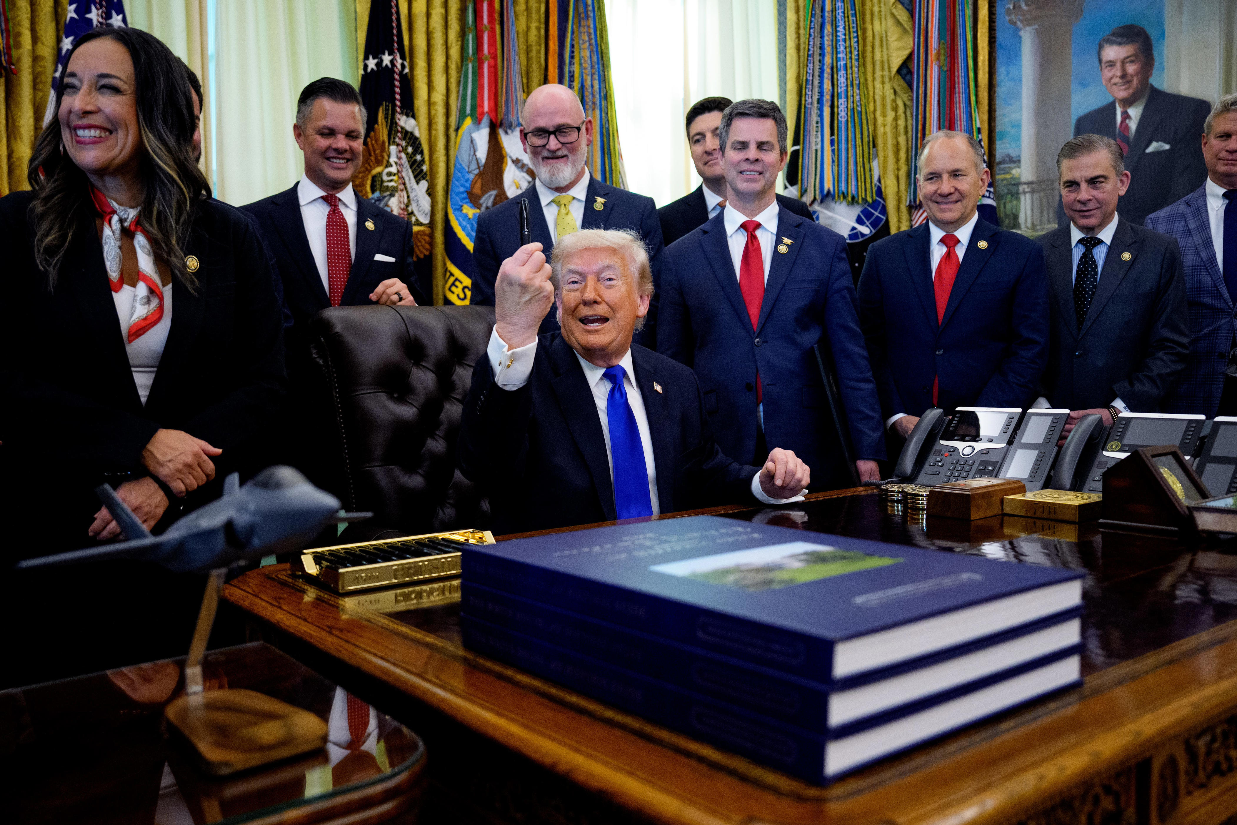 President Donald Trump is pictured holding up a pen as he speaks to reporters after signing executive orders in the Oval Office on April 30, 2026.