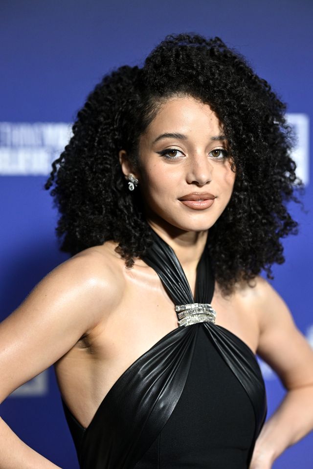 Person posing at an event wearing formal attire with styled hair