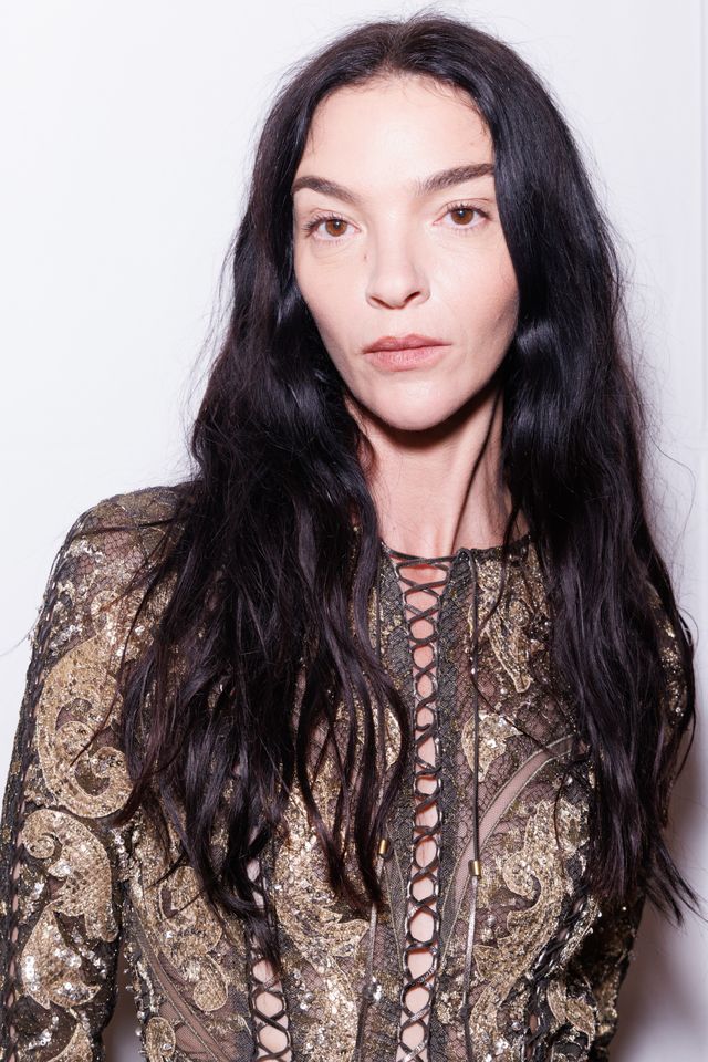 Mariacarla Boscono posing in a patterned outfit with long hair facing the camera directly