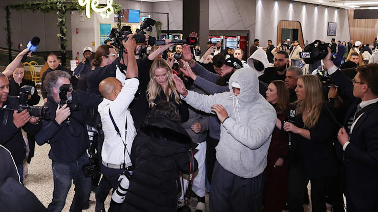 A group of supporters shield recently arrived people with links to Islamic State as they arrive at Melbourne Airport on May 7.