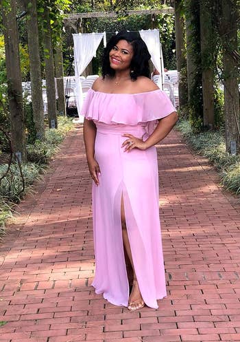 a reviewer in an off-shoulder ruffled pink gown with a leg slit, posing outdoors