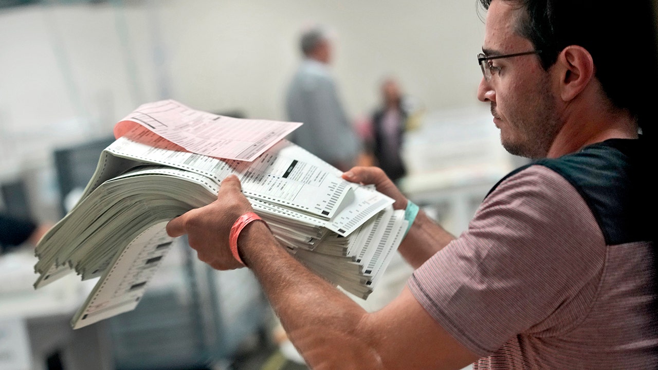 An elections official prepares to count mail-in ballots on the first day of tabulation, on Wednesday, Oct. 23, at the Maricopa County Recorder's Office in Phoenix.