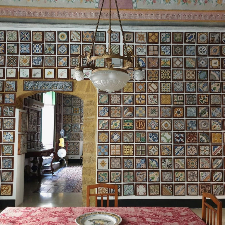 dining area with ornate tiled wall and chandelier