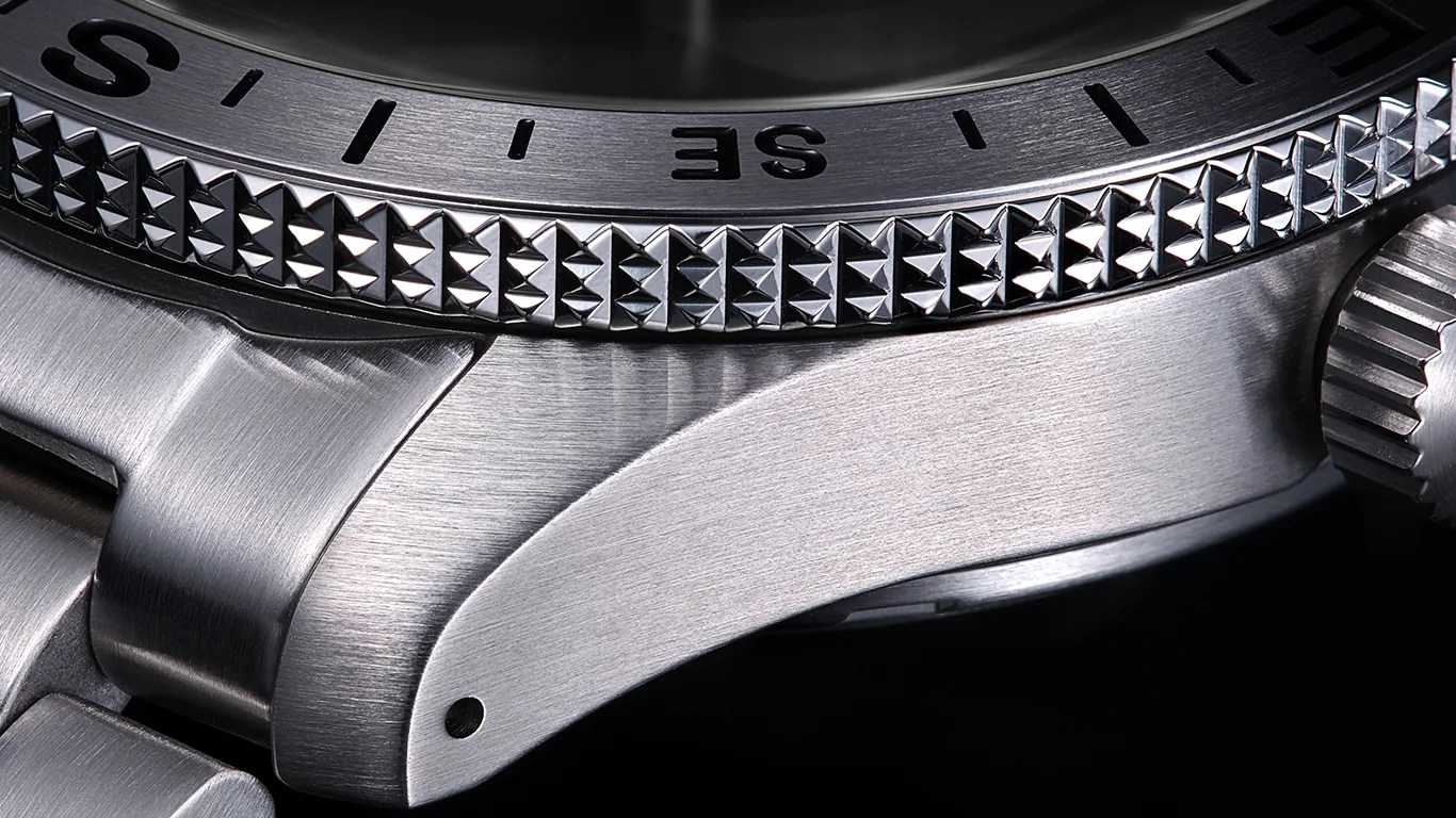 Close-up of a stainless steel watch case with a textured bezel and a crown on the right side.