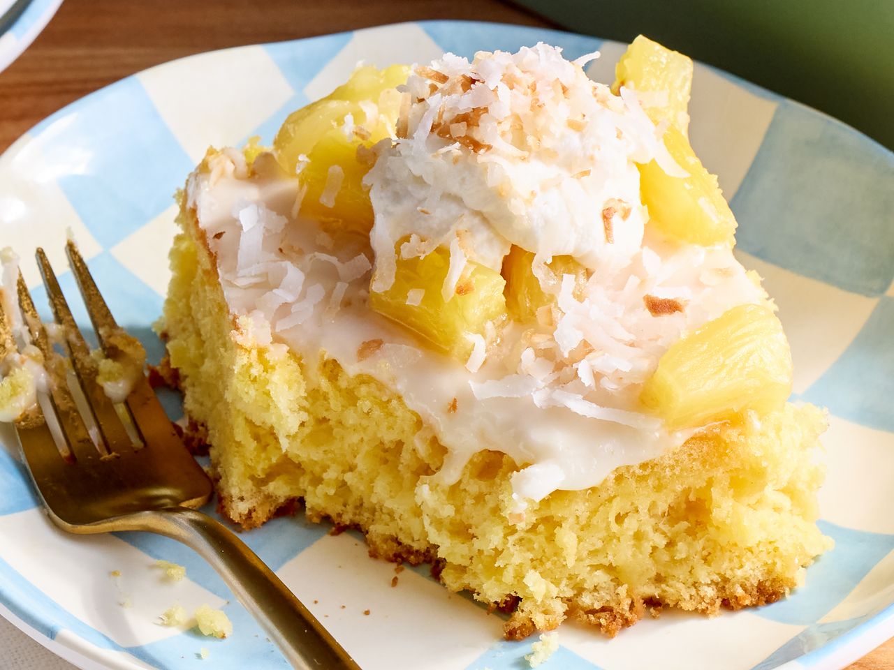 A slice of pineapple topped cake on a plate with a fork on the side
