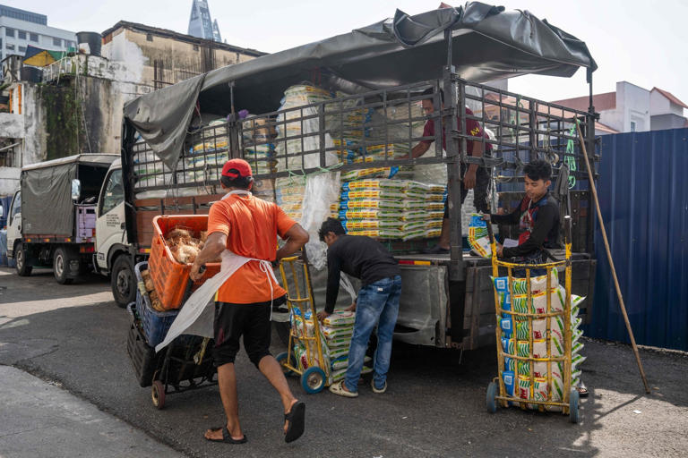 Workers unload sacks of rice outside a market in Kuala Lumpur, Malaysia on April 28. Photo: AFP