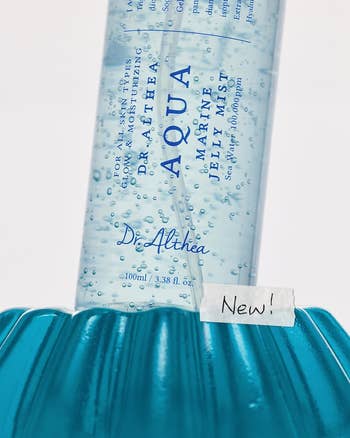 Aqua Marine Jelly Mist by Dr. Althea in a bottle with bubbles, shown on a blue surface with a