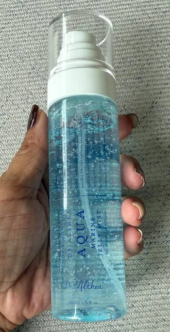 A person holds a bottle of Dr. Althea Aqua Marine Jelly Mist, a skincare product designed for hydration