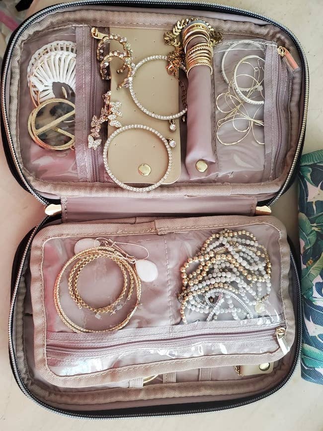 Reviewer's photo of the open jewelry organizer with assorted necklaces and earrings, suitable for travel