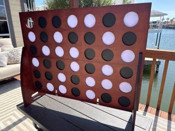 Giant outdoor Connect Four game set up on a patio overlooking a lake