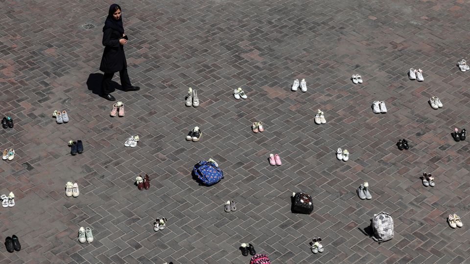 A woman walks past symbolic belongings laid on the ground at Valiasr Square in Tehran on April 24, 2026, in tribute to the schoolgirls in Minab killed during the initial February 28 airstrikes on Iran. - AFP/Getty Images