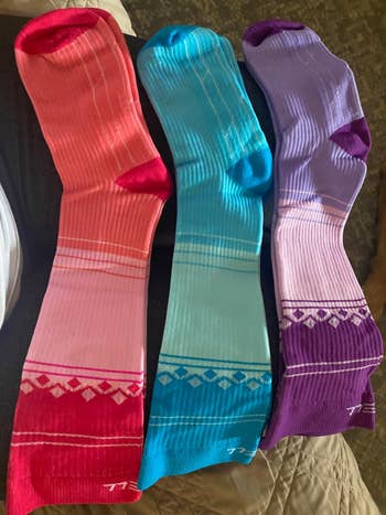 Three pairs of compression socks in red, blue, and purple, each with geometric patterns