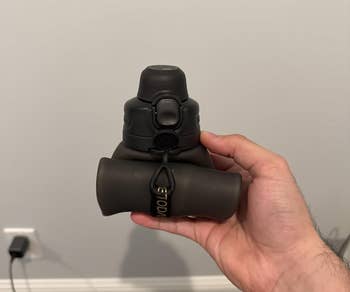 A person holds compact binoculars in one hand, showing the front view