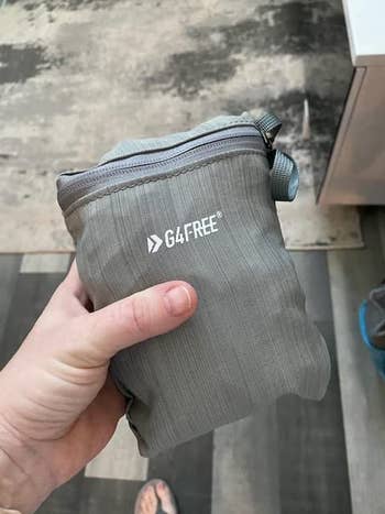 Hand holding a compact, folded G4Free bag