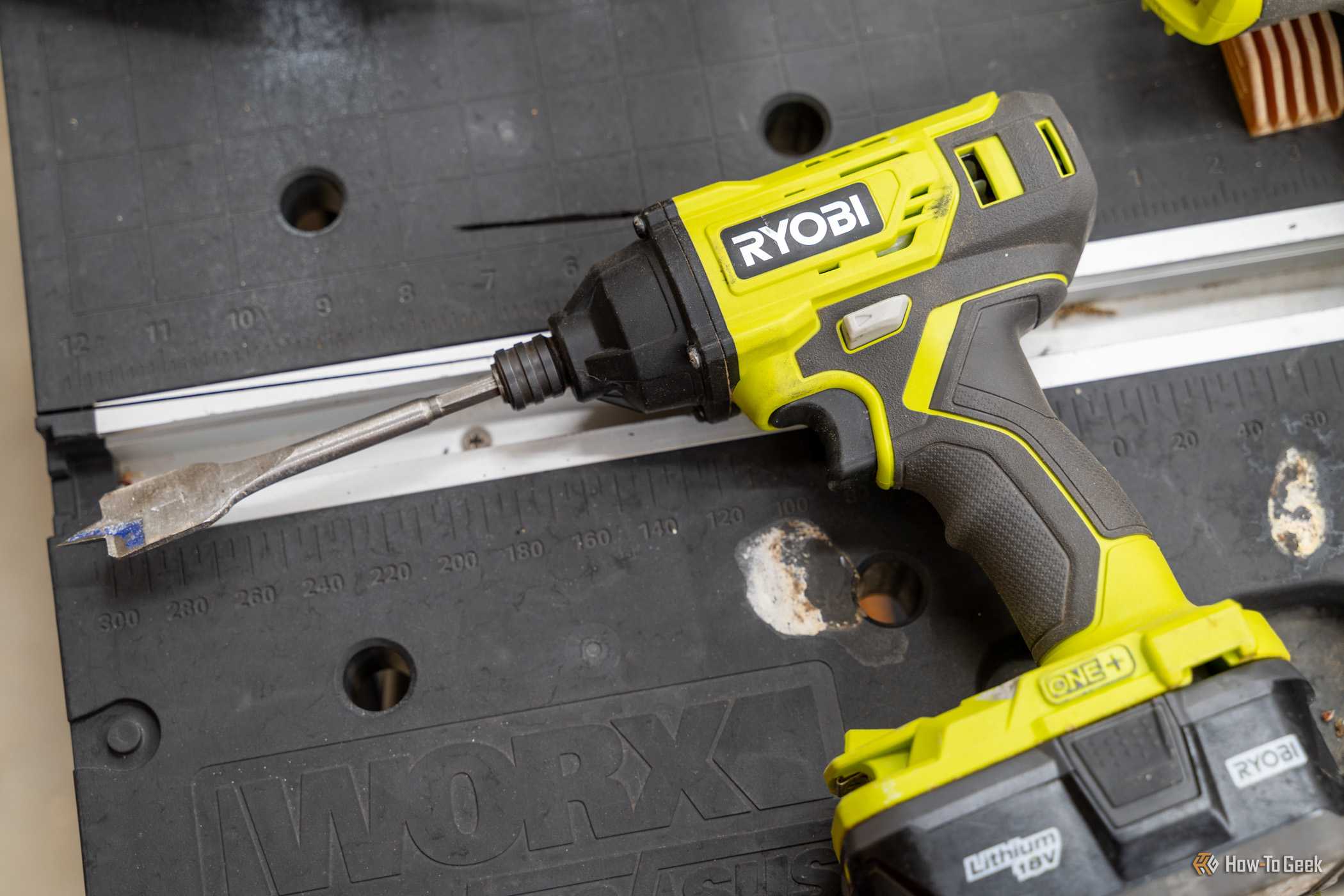 Close-up of a Ryobi ONE Plus 18V impact driver with a spade bit attached.