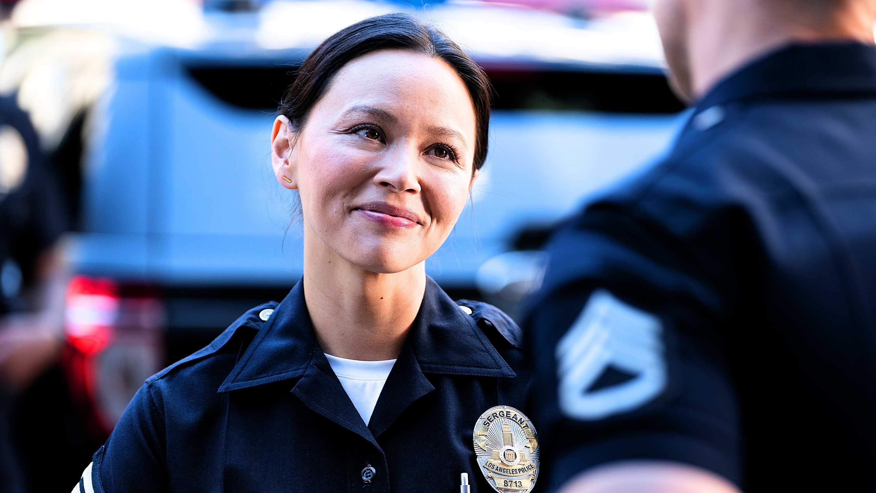 Lucy Chen in uniform smiling outside from The Rookie