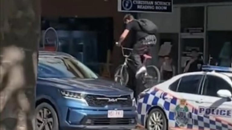 Footage of an individual riding a bike over a police car during a riot that erupted in Brisbane’s CBD on the weekend.
