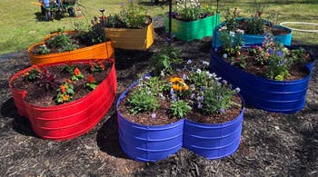 Colorful heart-shaped planters with various vibrant flowers displayed in a garden setting