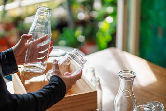 Hands placing empty glass jars into a wooden box