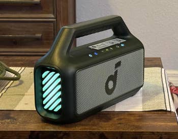 Portable speaker with a digital display and carrying handle on a wooden surface