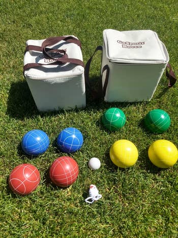 Bocce ball set on grass with bags and colorful balls: blue, red, green, yellow, a small white ball, and a toy figure. Great for outdoor games