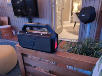 Portable speaker on a wood shelf in a casual room setting