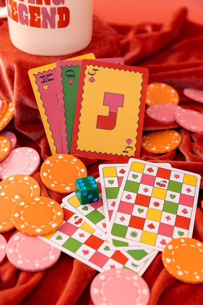 Playing cards and poker chips arranged on a red velvet fabric, with a dice beside them