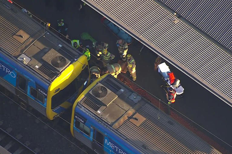 Emergency services workers strive to free the boy from under a train in North Melbourne on Monday.