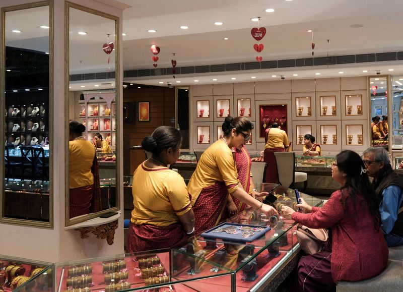 FILE PHOTO: Saleswomen show gold ornaments and jewellery to customers for purchase inside a Senco Gold &amp; Diamonds jewellery showroom in Kolkata