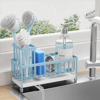 Sink organizer with brushes, sponge, scrubber, and soap dispenser, arranged near a faucet