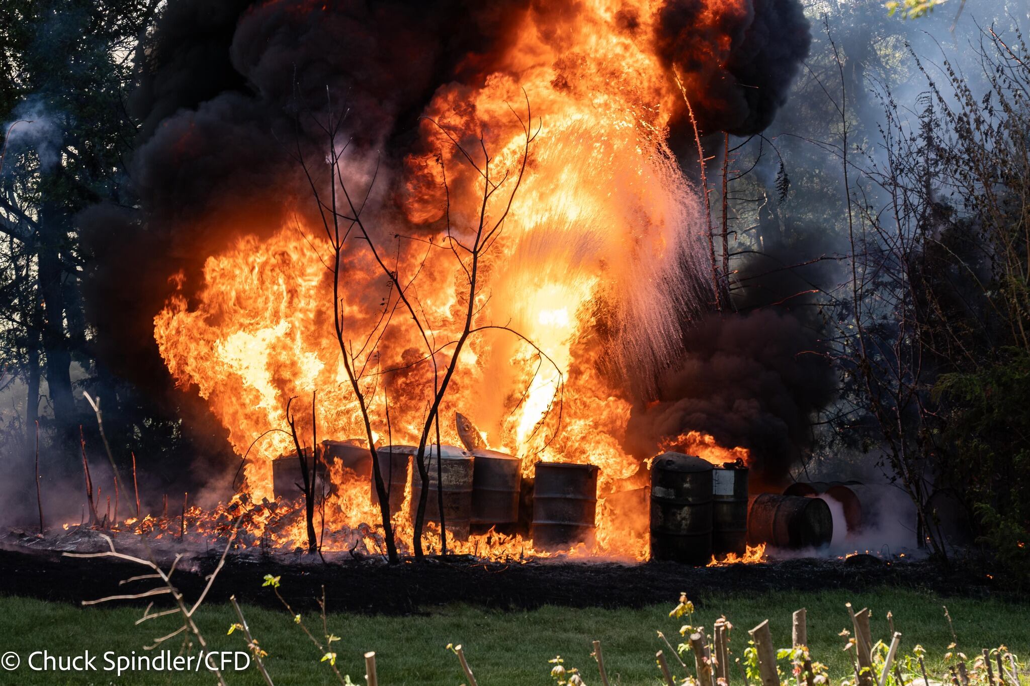 Grass fire spreads to oil drums in Creston