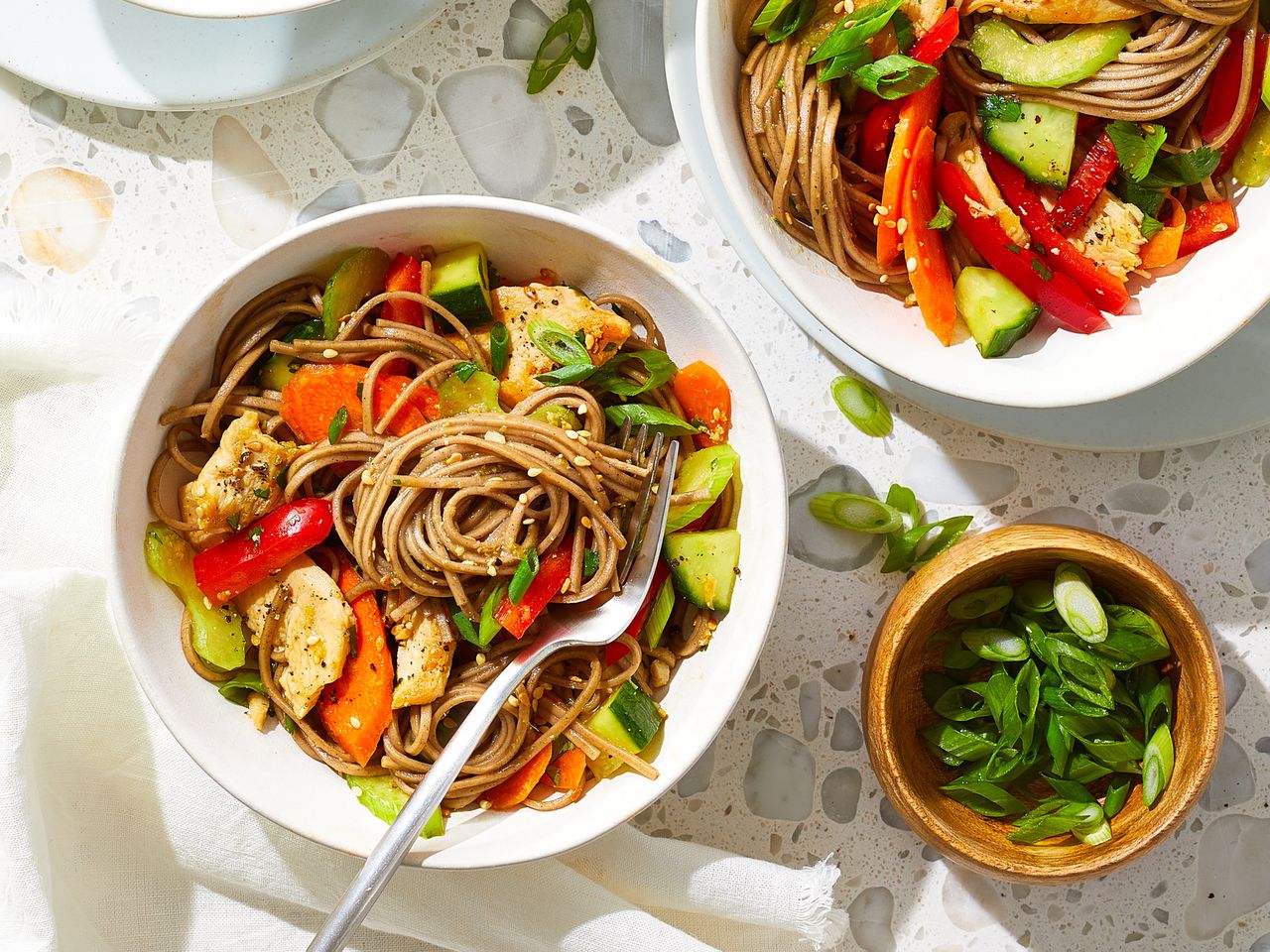 a close-up overhead view of a bowl of soba noodles salad with chicken and sesame.