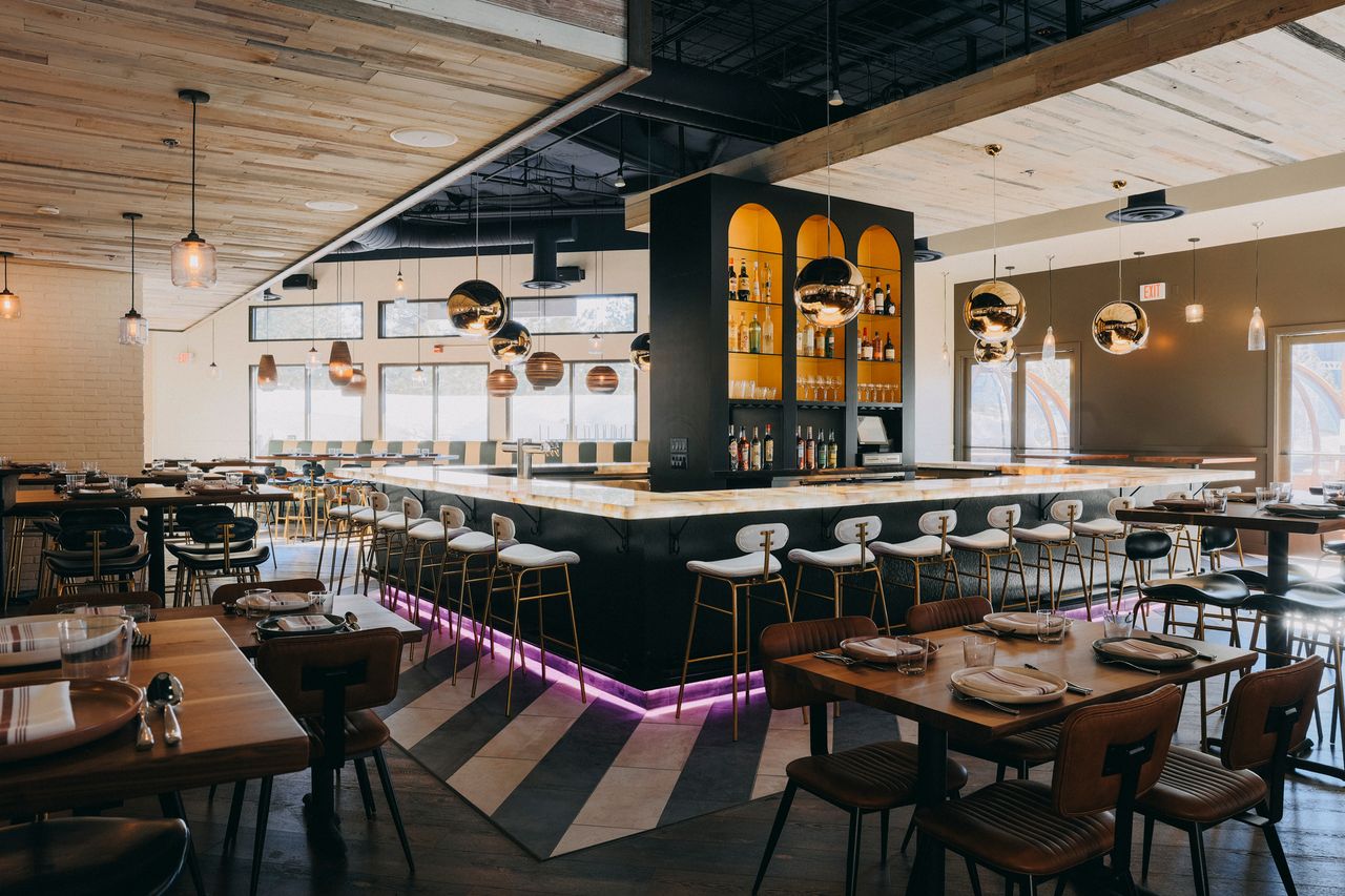 Restaurant interior with a modern bar at the center surrounded by tables and chairs
