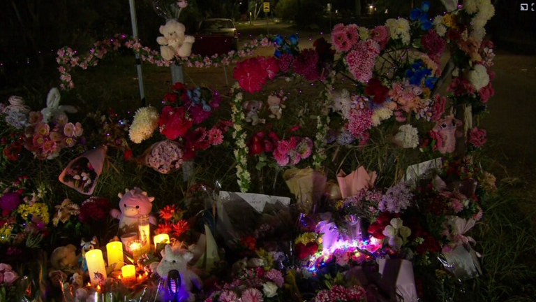 A large floral tribute has grown with bouquets of flowers, candles and soft toys.