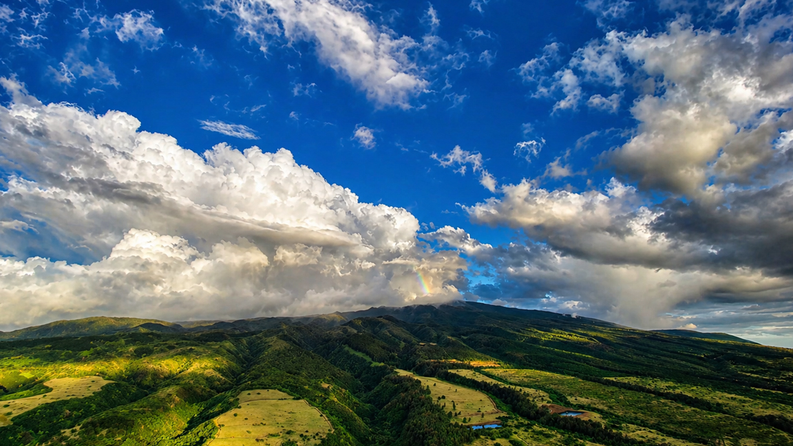 Expansive green valley beneath dramatic cloudscape